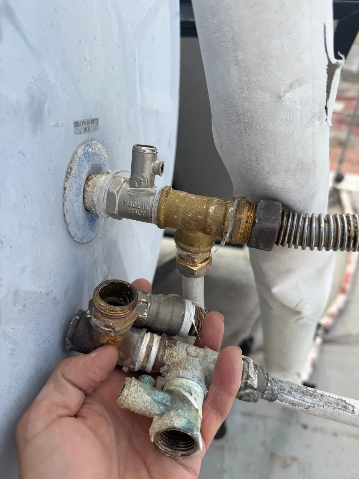 Válvula de seguridad y conexiones renovadas del acumulador solar térmico en Ayamonte, junto a las piezas retiradas
